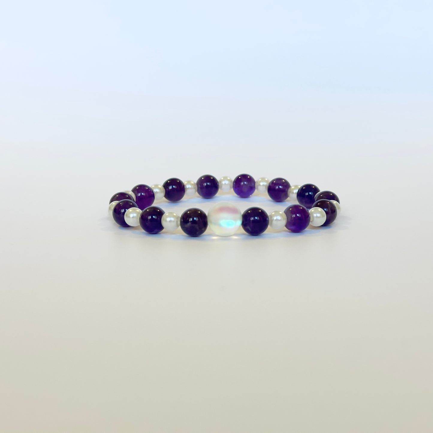 A sophisticated Amethyst & Pearl Bracelet featuring deep purple Amethyst beads, classic pearls, and a glowing aura bead for elegance and spiritual balance.