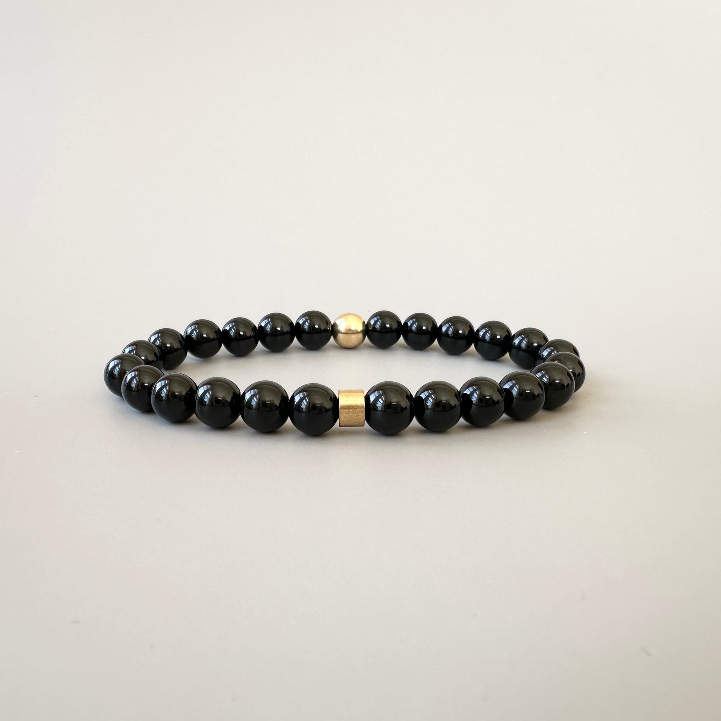 Close-up of smooth black onyx beads, showcasing their glossy black surface and timeless beauty.